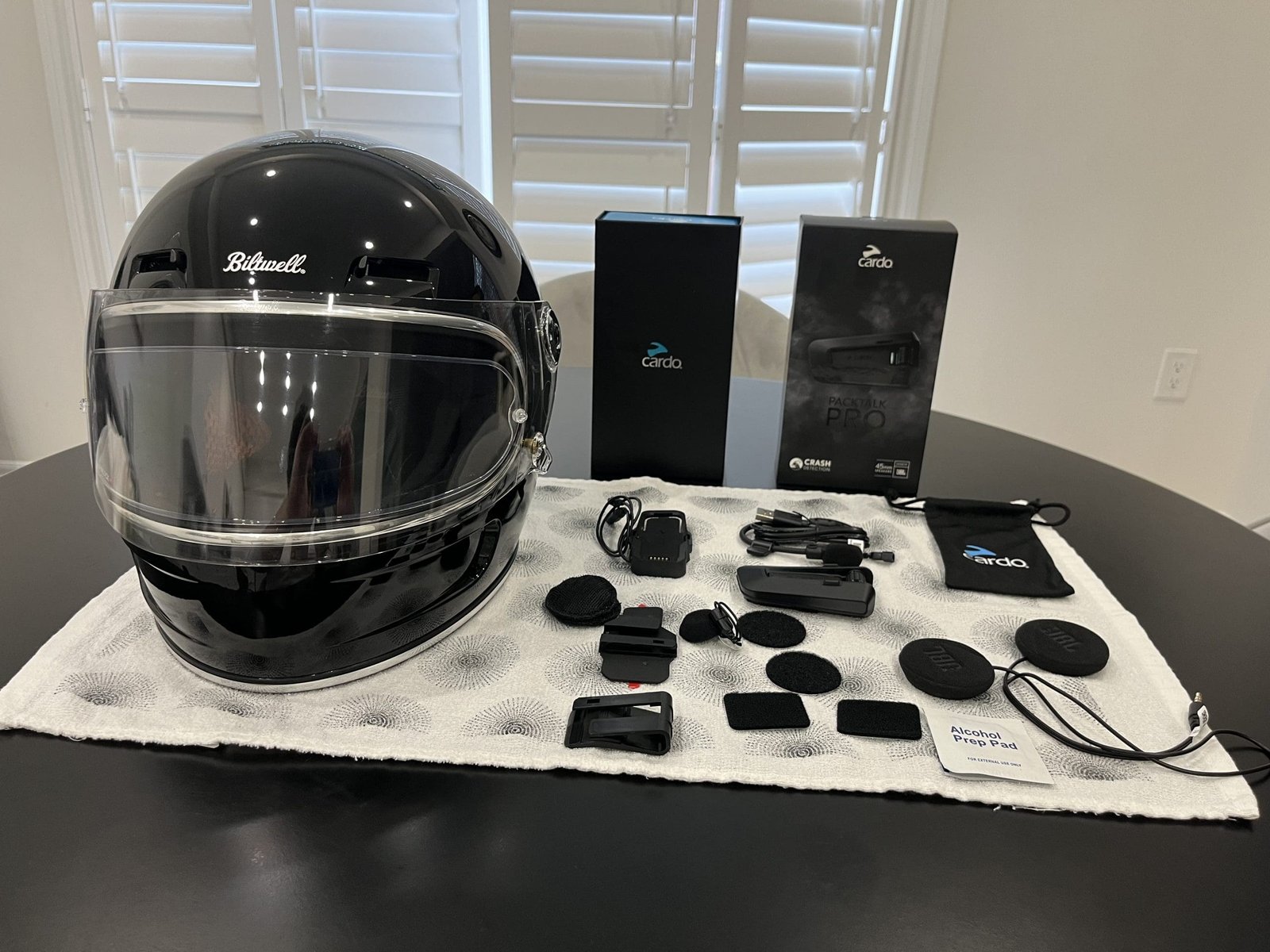 everything included with Cardo Packtalk Pro beside biltwell gringo SV on table being prepped for installation