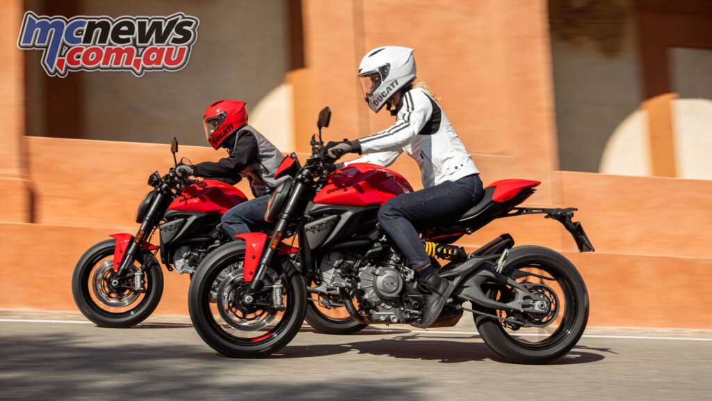 Rider on the 2026 Ducati Monster cornering on a public road, showing revised riding position and daytime running light