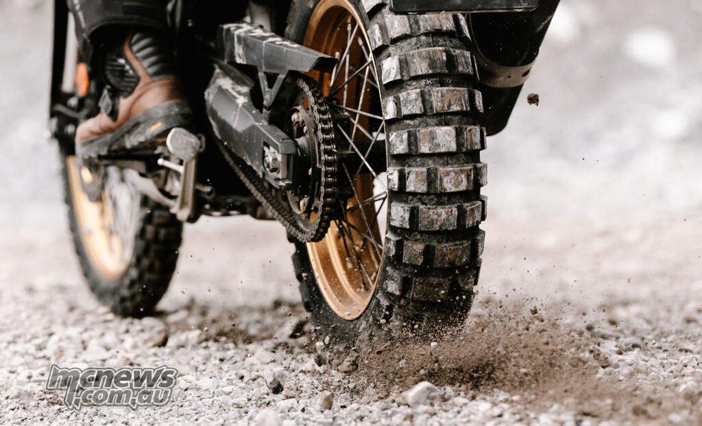 Close-up of a Continental TKC 80² tyre throwing gravel on a loose dirt surface.