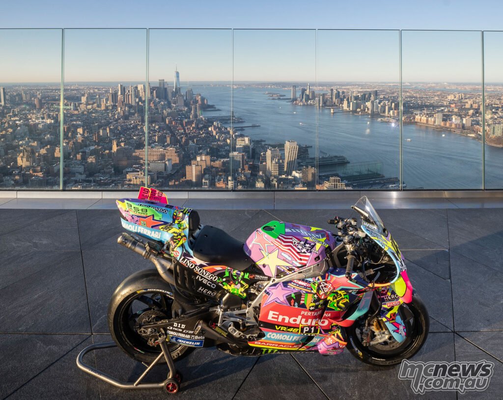 Pertamina Enduro VR46 Ducati MotoGP bike in special pop-art COTA livery on a rooftop observation deck in New York with Manhattan skyline behind.